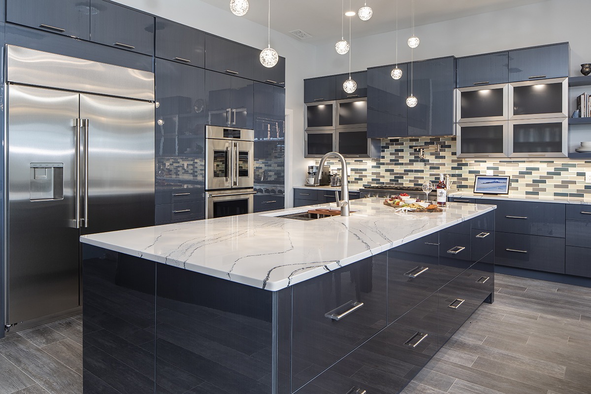Tủ bếp acrylic bóng navy, tay âm inox, phối đá trắng – sang trọng, hiện đại.